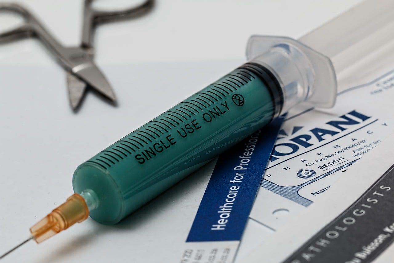 A syringe on top of medical papers